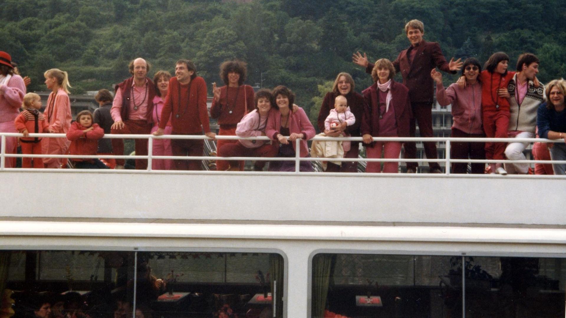 Menschen in roter und pinker Freizeitkleidung posieren auf dem Deck eines Ausflugsschiffs. Menschen in roter und pinker Freizeitkleidung posieren auf dem Deck eines Ausflugsschiffs.