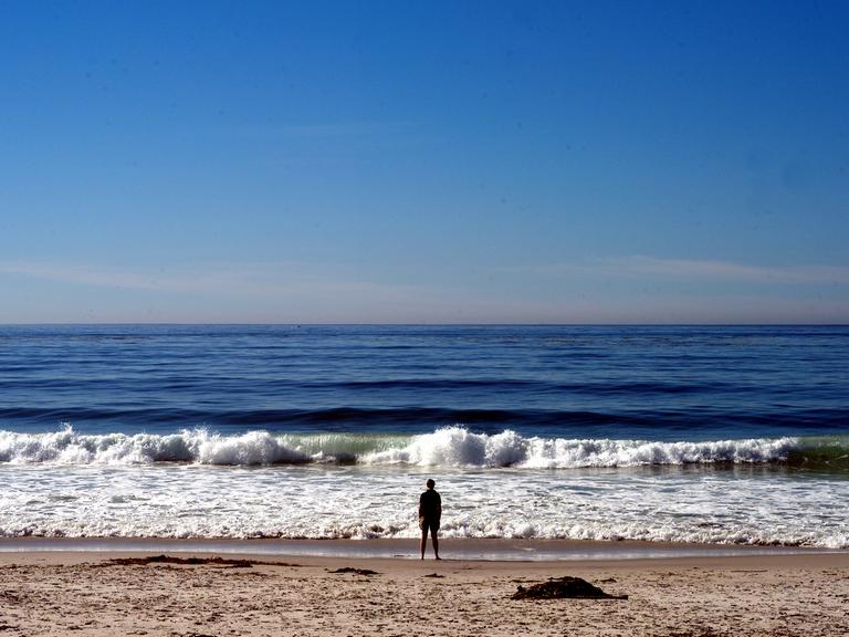 Eine Mann steht am Pazifikstrand von Carmel in Kalifornien.