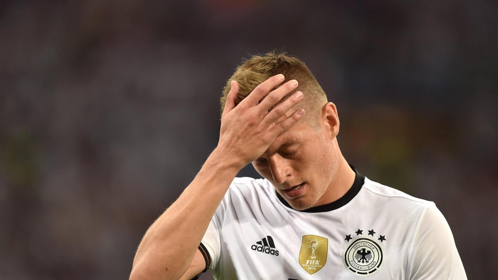 Der deutsche Fußball-Spieler Toni Kroos hält sich die Hand vor den Kopf. Der deutsche Fußball-Spieler Toni Kroos hält sich die Hand vor den Kopf.