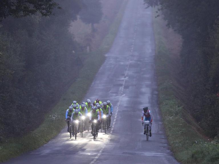 Ein Radteam fährt bei dem 1200km Rennen Paris-Brest-Paris durch den morgendlichen Nebel.