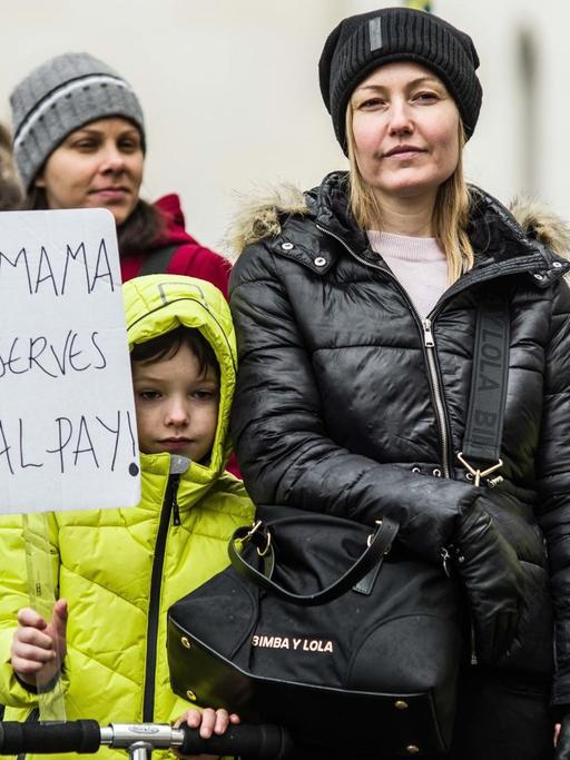Frauen und Kinder demonstrieren in München für eine bessere Bezahlung von Frauen. Sie halten ein Schild mit der Aufschrift "My Mama deserves equal pay" hoch.