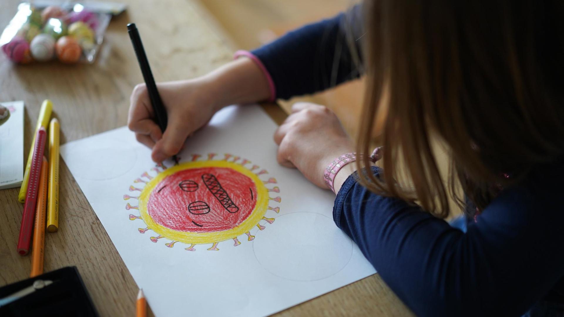 Ein Mädchen sitzt am Tisch und versucht die Form eines Corona-Virus nachzuzeichnen. Ein Mädchen sitzt am Tisch und versucht die Form eines Corona-Virus nachzuzeichnen.
