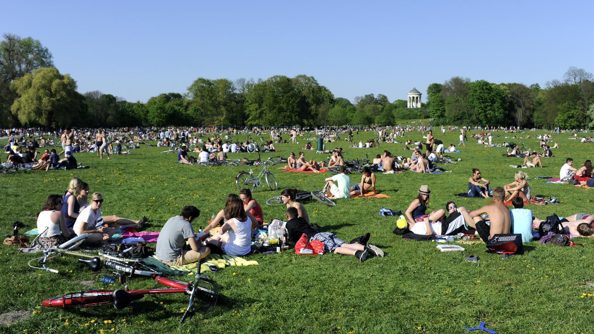 Viele Ausflügler sitzen im Englischen Garten in München auf einer Wiese. Viele Ausflügler sitzen im Englischen Garten in München auf einer Wiese.
