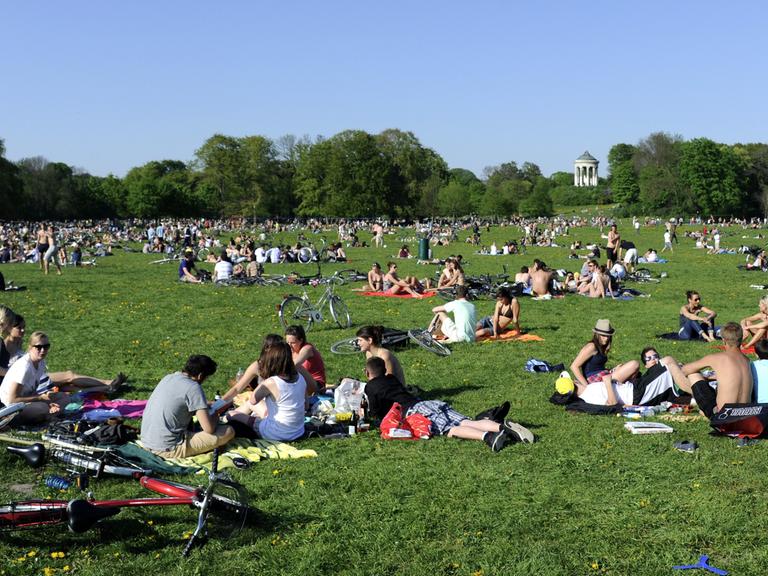 Viele Ausflügler sitzen im Englischen Garten in München auf einer Wiese.