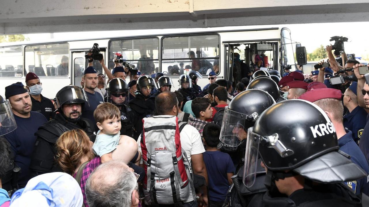 Die ungarische Polizei geleitet Flüchtlinge in Bicske zu einem Bus. Die ungarische Polizei geleitet Flüchtlinge in Bicske zu einem Bus.