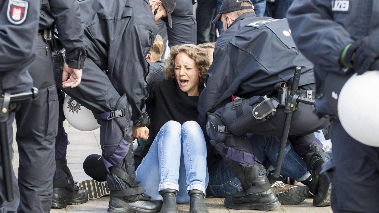 Eine Demonstrantin wird von Polizisten abgeführt