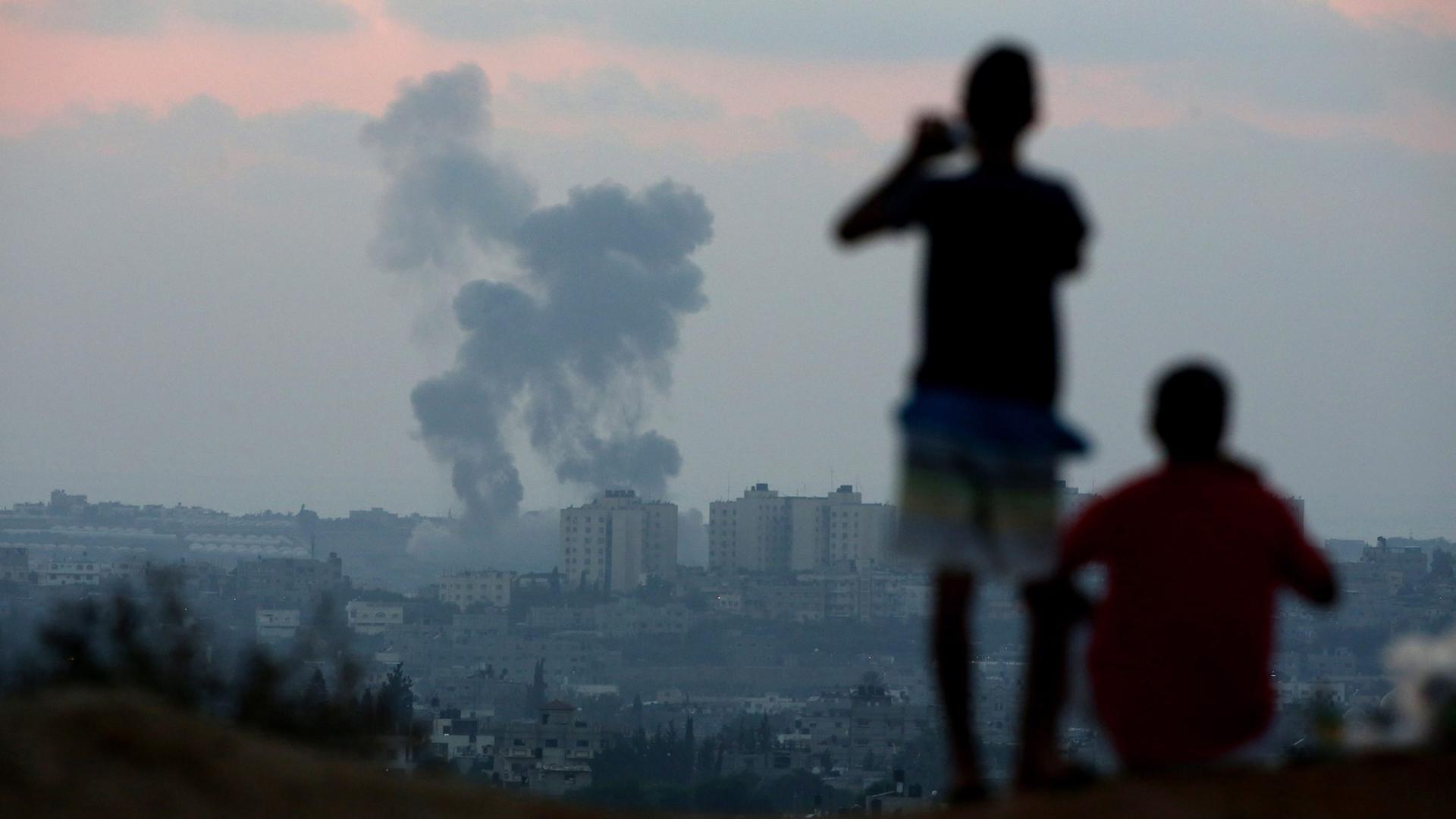 Menschen betrachten eine Explosion im Gaza-Streifen