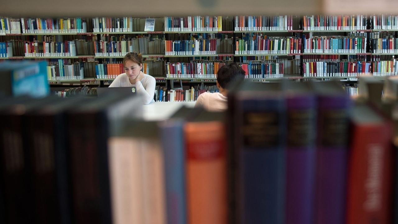 Besucher der Amerika-Gedenkbibliothek in Berlin sitzen zwischen Bücherregalen. Besucher der Amerika-Gedenkbibliothek in Berlin sitzen zwischen Bücherregalen.