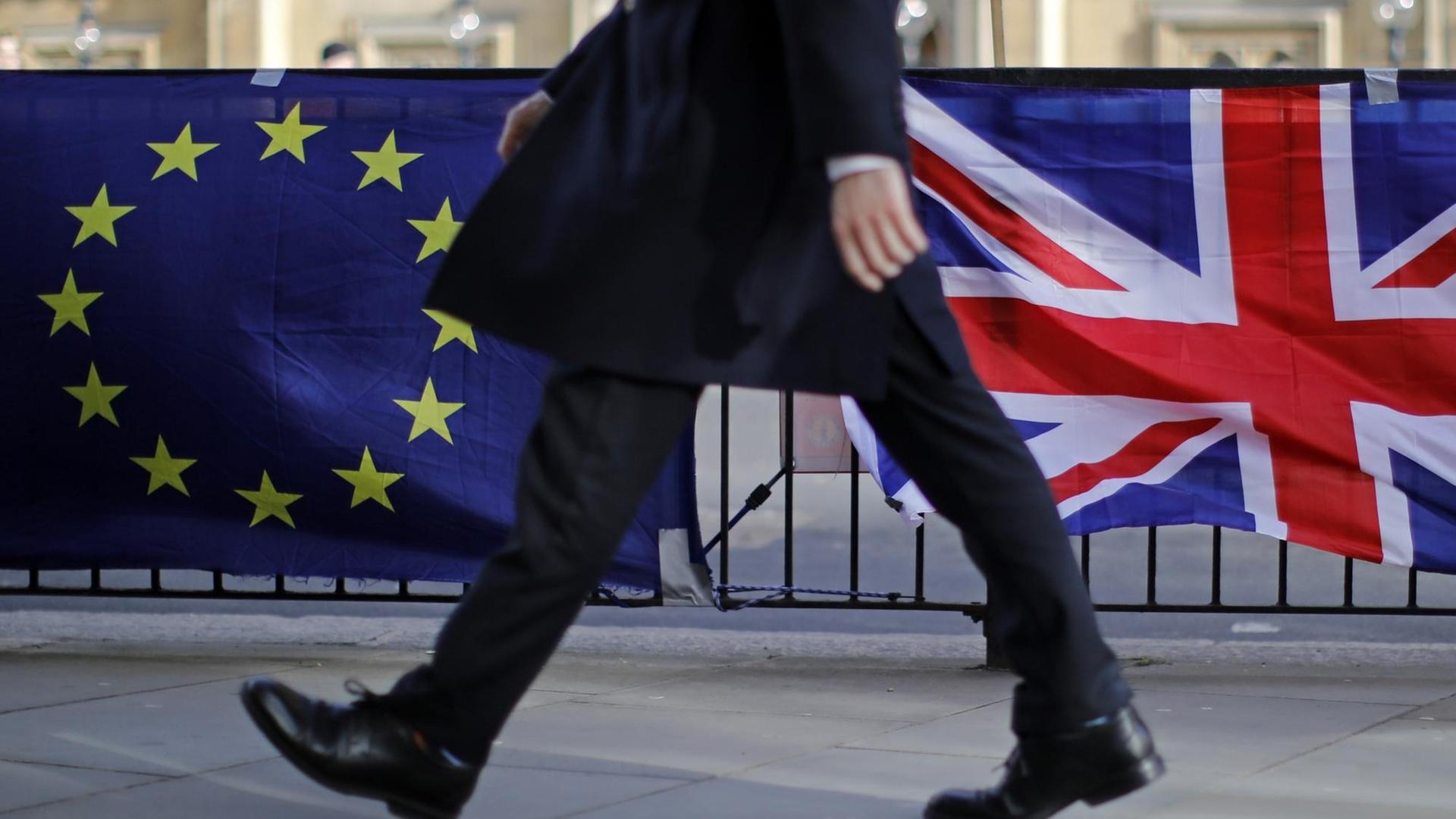 Ein Mann geht vor dem Parlament in London an Flaggen der EU und Großbritanniens vorbei Ein Mann geht vor dem Parlament in London an Flaggen der EU und Großbritanniens vorbei