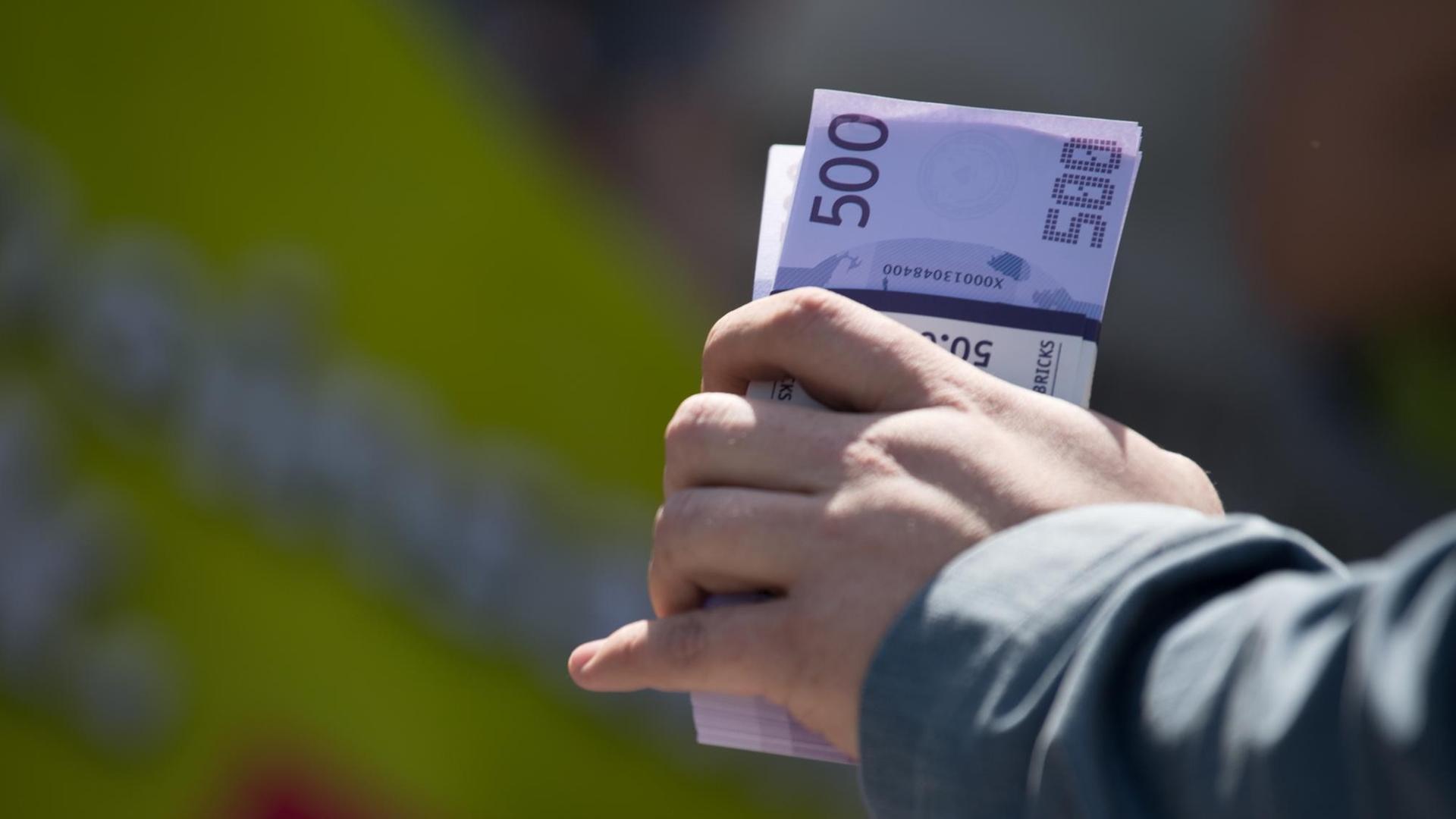 15.04.2018, Brandenburg, Potsdam: Kurz vor dem Start der dritten Verhandlungsrunde im Tarifstreit für den öffentlichen Dienst protestieren Mitglieder der Gewerkschaft Verdi vor dem Tagungshotel. Ein Demonstrant hält ein Bündel mit Spielgeld. Bisher lehnen die Arbeitgeber die Gewerkschaftsforderungen nach sechs Prozent mehr Geld, mindestens aber 200 Euro, ab. Es geht um 2,3 Millionen Beschäftigte bei Kommunen und beim Bund. 15.04.2018, Brandenburg, Potsdam: Kurz vor dem Start der dritten Verhandlungsrunde im Tarifstreit für den öffentlichen Dienst protestieren Mitglieder der Gewerkschaft Verdi vor dem Tagungshotel. Ein Demonstrant hält ein Bündel mit Spielgeld. Bisher lehnen die Arbeitgeber die Gewerkschaftsforderungen nach sechs Prozent mehr Geld, mindestens aber 200 Euro, ab. Es geht um 2,3 Millionen Beschäftigte bei Kommunen und beim Bund.