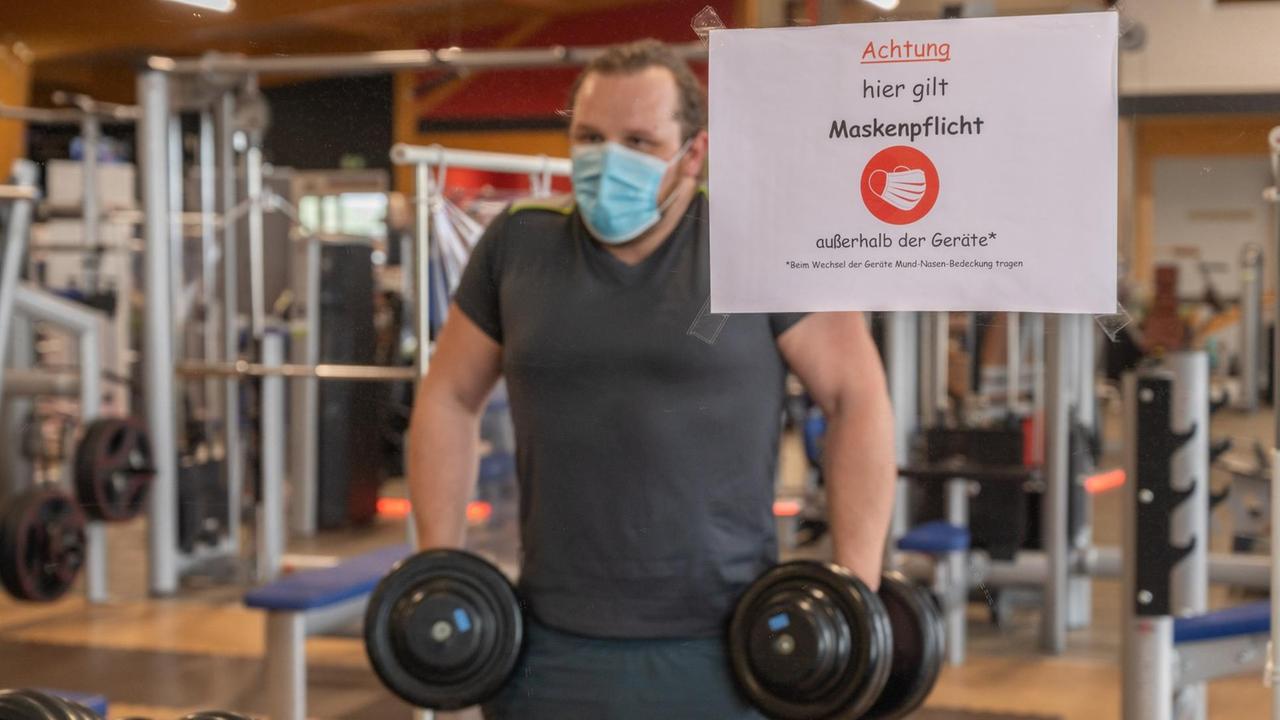 Ein Mann trainiert mit Mund-Nasen-Schutz in einem Fitnessstudio. 