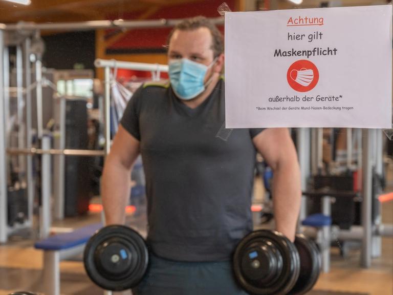 Ein Mann trainiert mit Mund-Nasen-Schutz in einem Fitnessstudio.