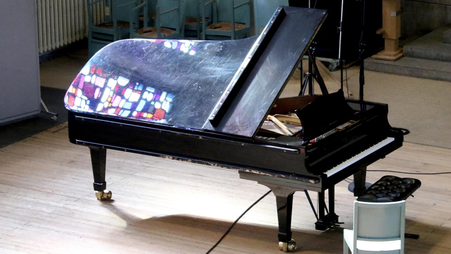 Auf einem schwarzen Flügel spiegeln sich farbige Lichtflecken von bunten Kirchenfenstern Auf einem schwarzen Flügel spiegeln sich farbige Lichtflecken von bunten Kirchenfenstern