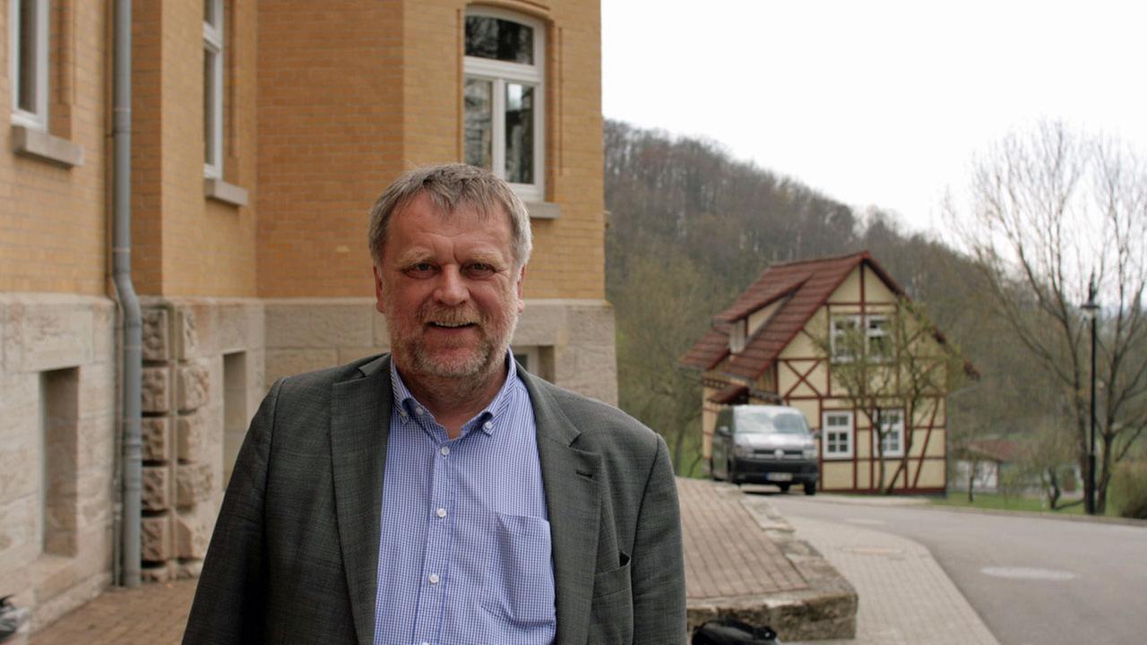 Schulleider Burkhard Werner steht vor dem Schulgebäude, im Hintergrund ein Fachwerkhaus.