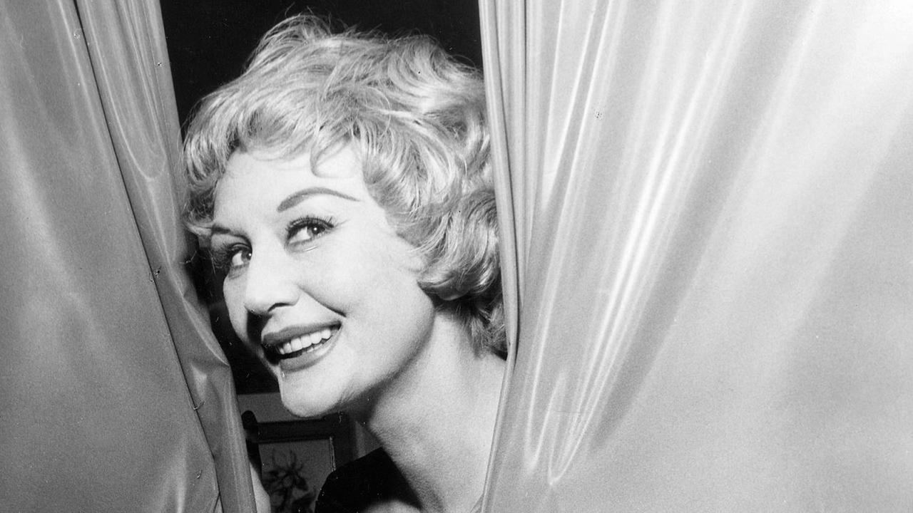 Die Sängerin Evelyn Künneke (*15.12.1921-28.04.2001). Sie lächelt frech zwischen einem Vorhang, 1959. Die Sängerin Evelyn Künneke (*15.12.1921-28.04.2001). Sie lächelt frech zwischen einem Vorhang, 1959.