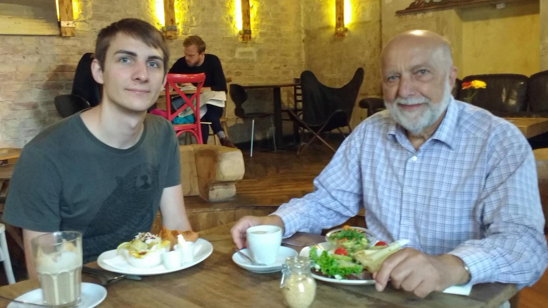 Sören und Günther Götz sitzen an einem Tischen nebeneinander Sören und Günther Götz sitzen an einem Tischen nebeneinander