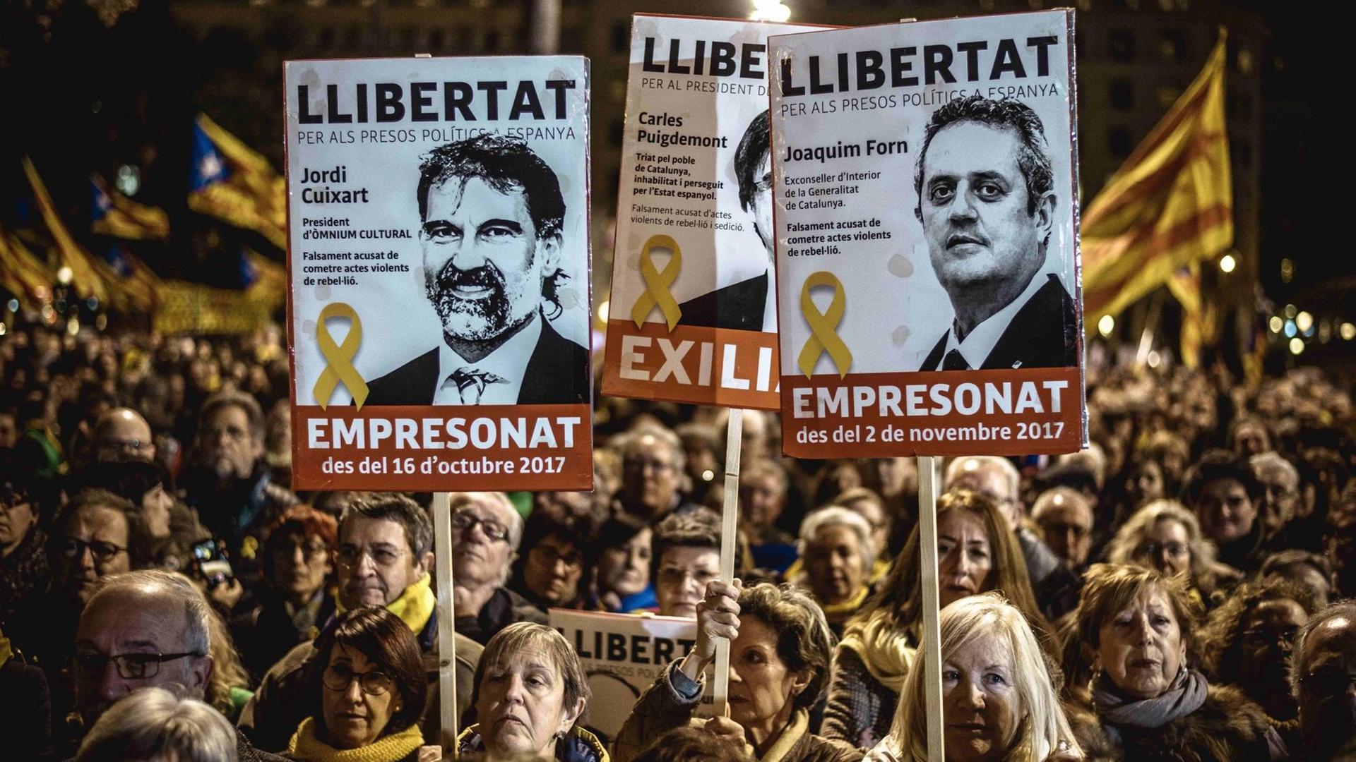 Demonstranten zeigen Plakate mit Abbildungen inhaftierter katalanischer Separatistenführer bei einem Protest gegen den gerichtlichen Prozess, der gegen sie geführt wird.