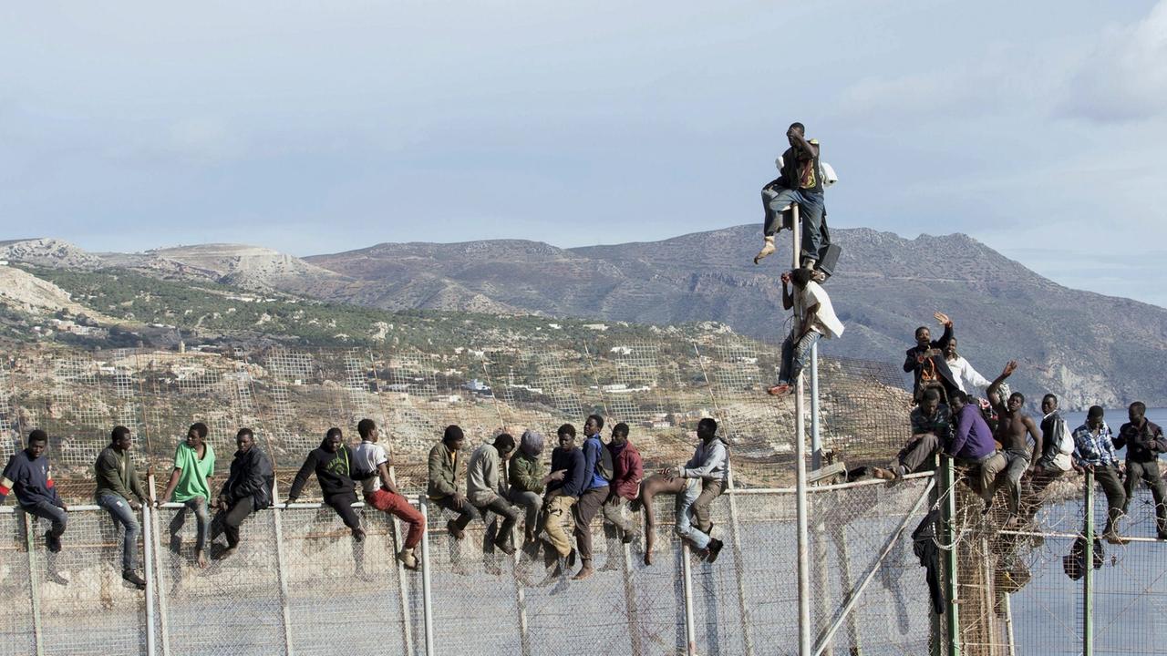 Afrikanische Flüchtlinge versuchen, den Grenzzaun zur spanischen Exklave Melilla zu überwinden. Afrikanische Flüchtlinge versuchen, den Grenzzaun zur spanischen Exklave Melilla zu überwinden.
