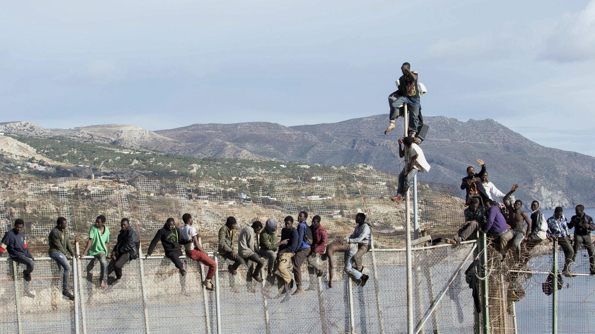 Afrikanische Flüchtlinge versuchen, den Grenzzaun zur spanischen Exklave Melilla zu überwinden. Afrikanische Flüchtlinge versuchen, den Grenzzaun zur spanischen Exklave Melilla zu überwinden.