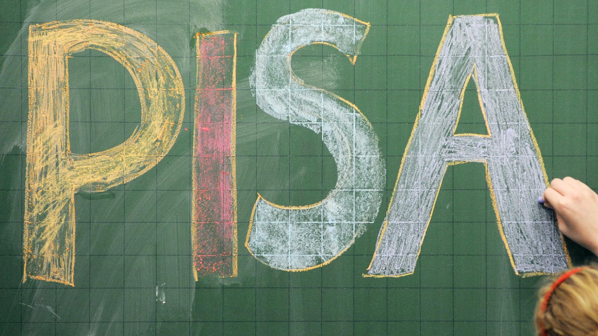 Eine Schülerin schreibt das Wort "PISA" auf eine Tafel.