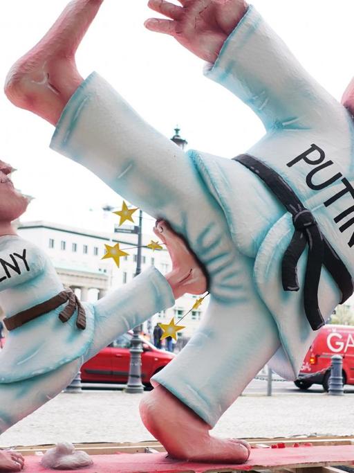 Eine drei Meter hohe Installation zeigt vor dem Brandenburger Tor einen "kleinen Alexej Nawalny", wie er den "übergroßen Wladimir Putin" tritt. Die Figur war Teil des Karnevalswagen des diesjährigen Düsseldorfer Rosenmontagszugs, den die Aktivisten von „Freies Russland NRW“ nach Berlin brachten. Entworfen hat sie der Düsseldorfer Künstler J. Tilly.