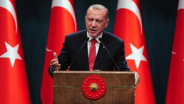 Der türkische Präsident Erdogan an einem Rednerpult vor mehreren türkischen Flaggen. Der türkische Präsident Erdogan an einem Rednerpult vor mehreren türkischen Flaggen.