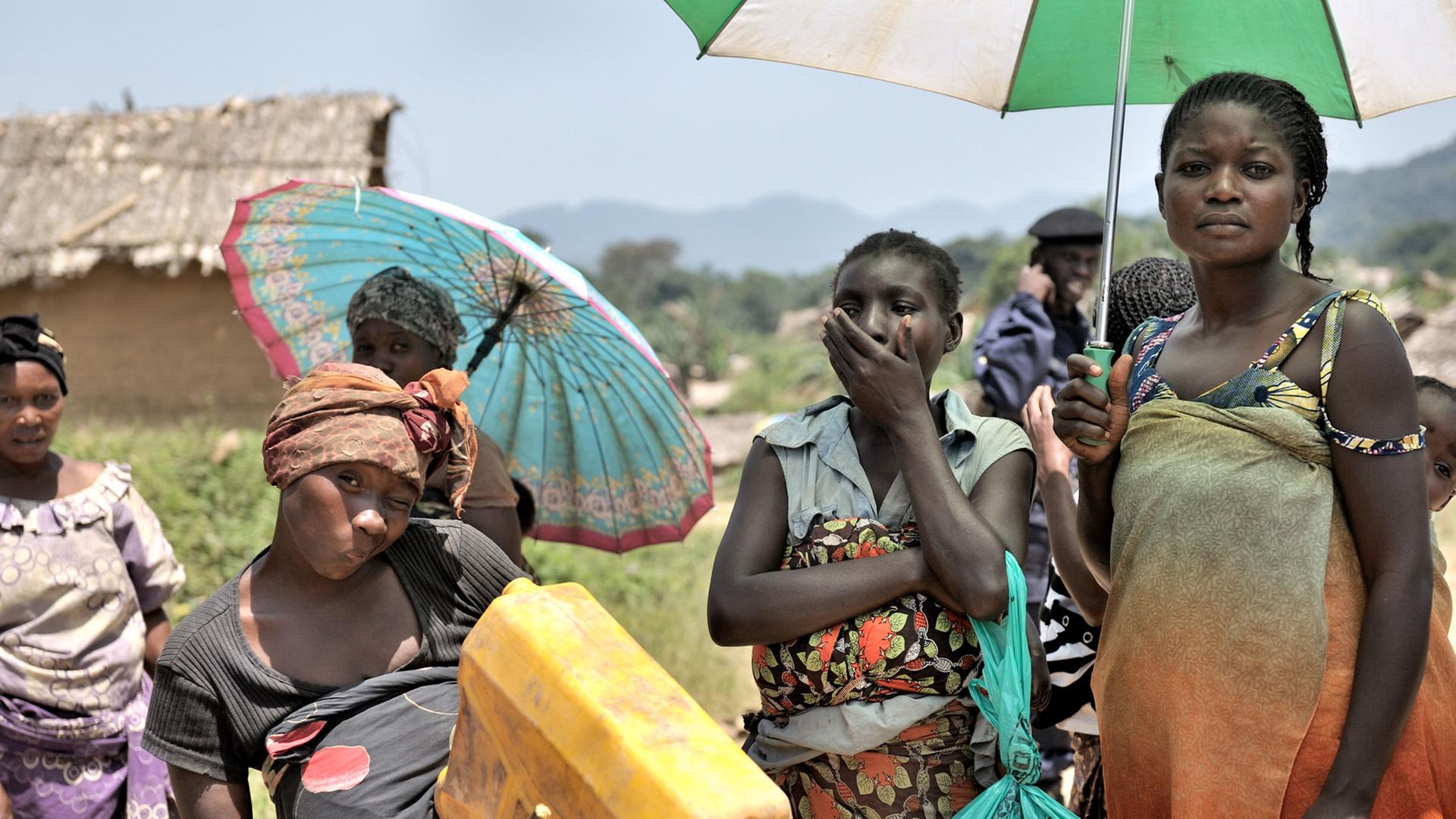 Mehrere Frauen stehen mit Sonnenschirmen in einem Dorf im Ostkongo. Sie wurden 2012 Opfer von Massenvergewaltigungen. Mehrere Frauen stehen mit Sonnenschirmen in einem Dorf im Ostkongo. Sie wurden 2012 Opfer von Massenvergewaltigungen.