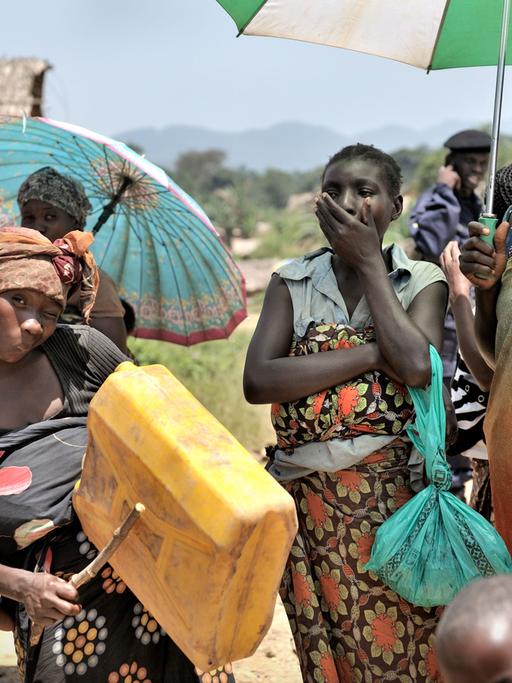 Mehrere Frauen stehen mit Sonnenschirmen in einem Dorf im Ostkongo. Sie wurden 2012 Opfer von Massenvergewaltigungen.