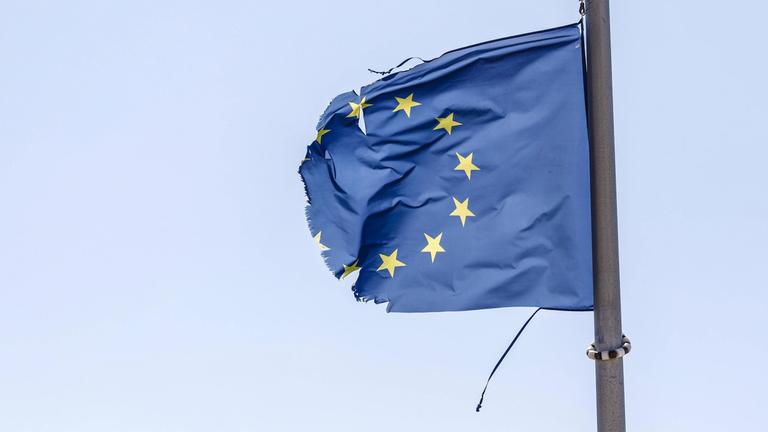 Eine zerrissene EU-Fahne flattert im Wind.