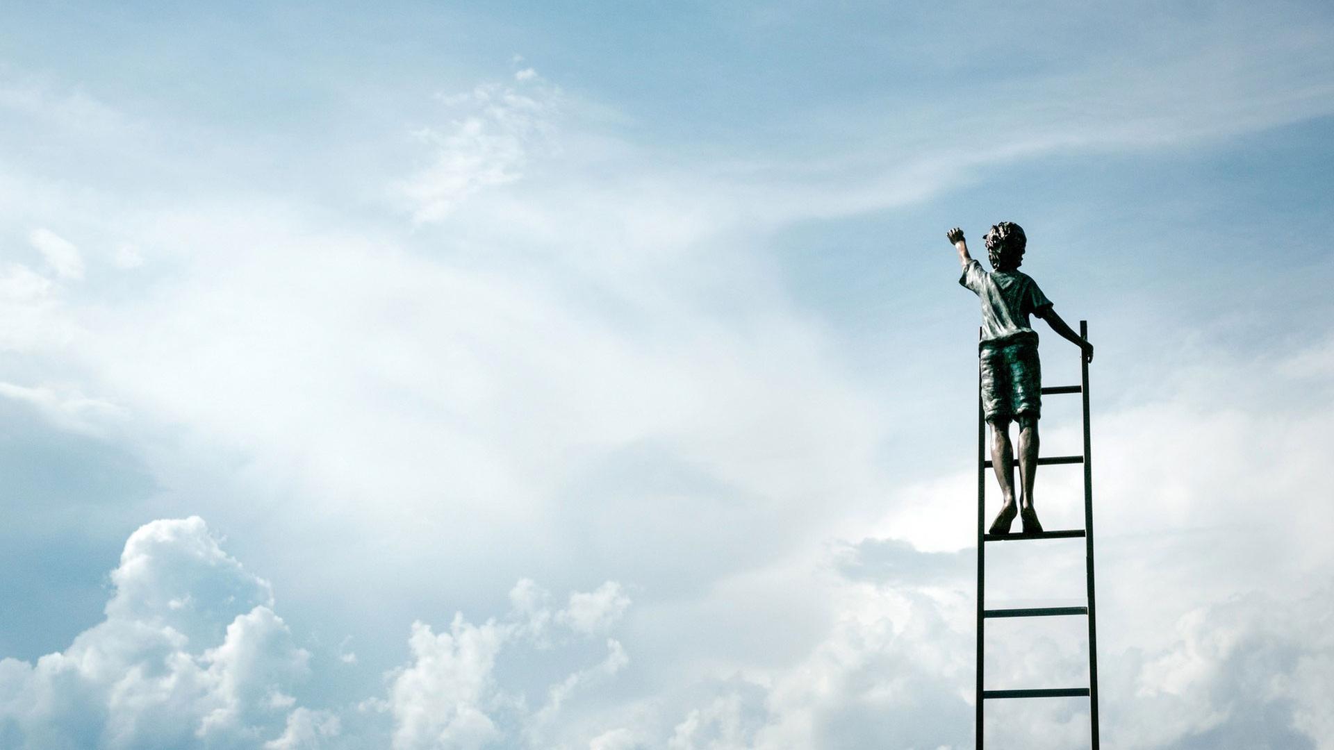 Ein Junge in kurzen Hosen steht auf einer Leiter und streckt die Hand zum Himmel aus. Ein Junge in kurzen Hosen steht auf einer Leiter und streckt die Hand zum Himmel aus.