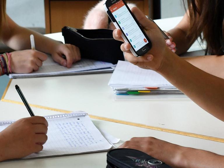 Schüler hält im Unterricht ein Handy in den Händen
