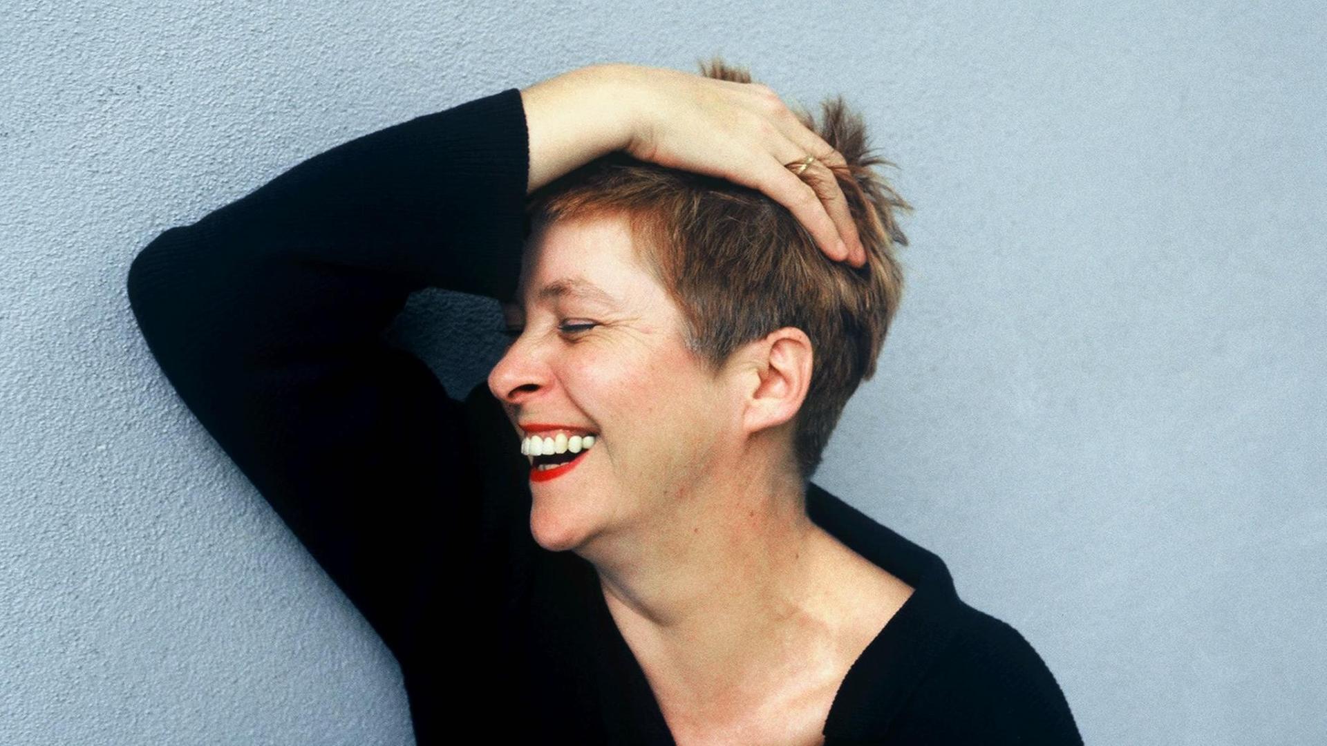 Lieselotte '' Pieke '' Biermann, deutsche Journalistin, Autorin und Uebersetzerin, rauft sich lachend die Haare vor einer blauen Hauswand. Lieselotte '' Pieke '' Biermann, deutsche Journalistin, Autorin und Uebersetzerin, rauft sich lachend die Haare vor einer blauen Hauswand.