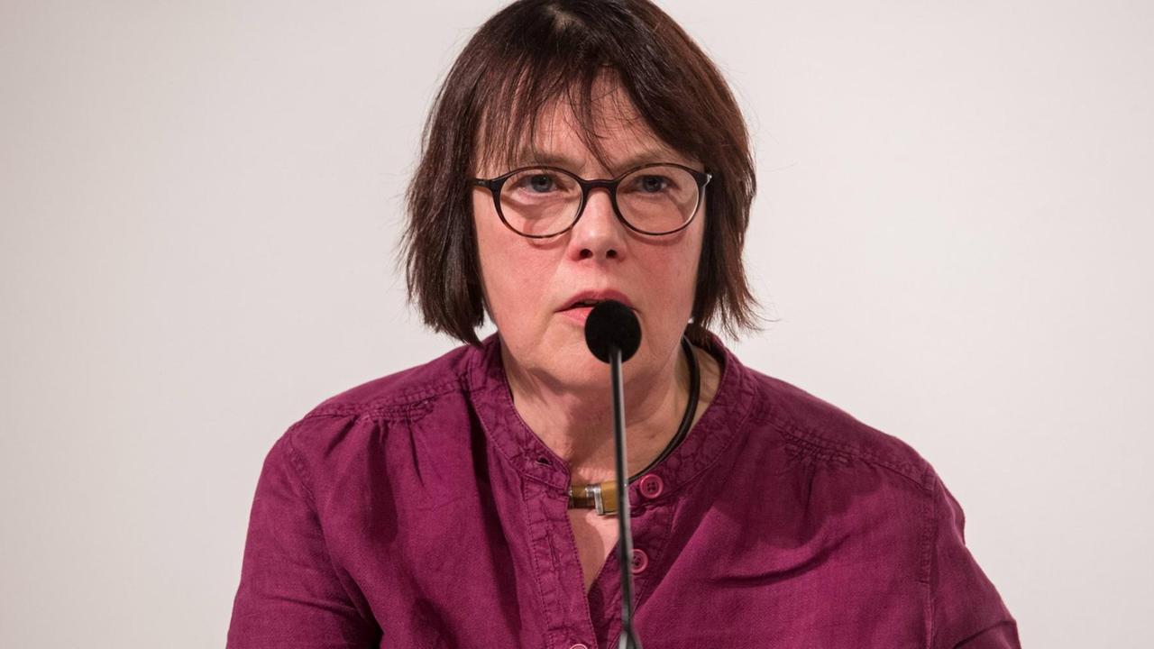 Die Schriftstellerin Kathrin Schmidt mit Brille und dunkelroter Bluse spricht in ein Tischmikrofon.