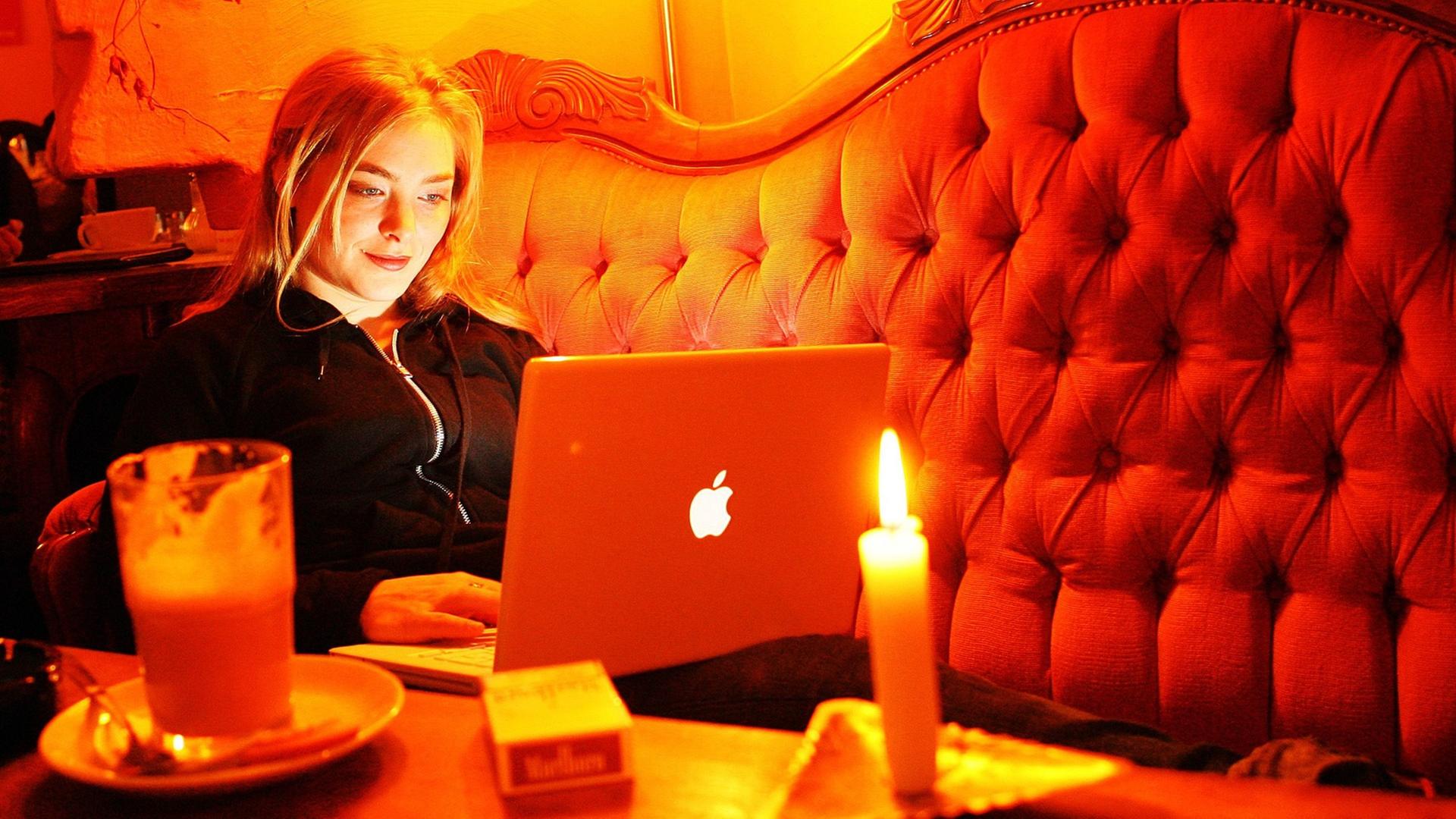 Ein junge Frau sitzt in einem Internetcafe.