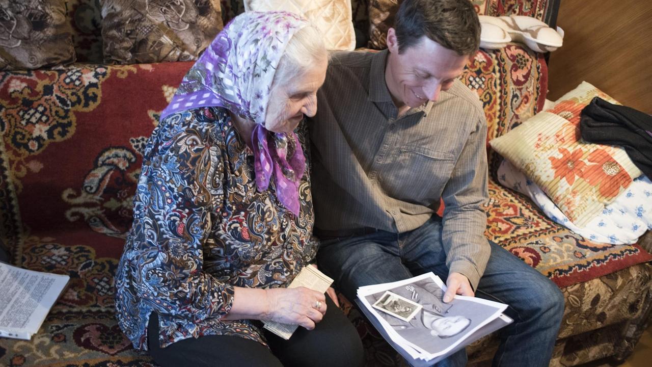 Sebastian Heinzel und Valentina Dimitreyewna sitzen auf einer Couch und blättern in Dokumenten. Sebastian Heinzel und Valentina Dimitreyewna sitzen auf einer Couch und blättern in Dokumenten.