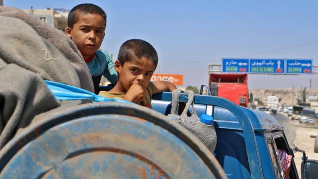 Auf einem Lastwagen hocken Kinder neben Gepäck, sie fliehen aus Idlib nach Norden.