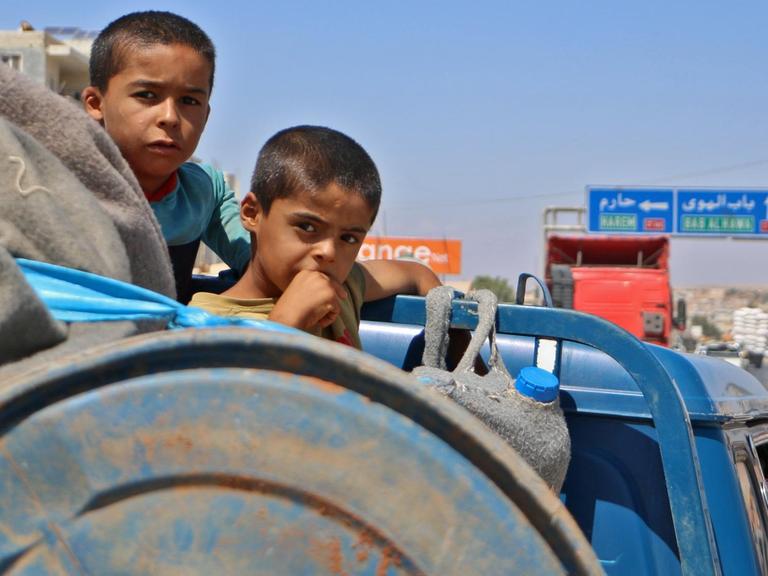 Auf einem Lastwagen hocken Kinder neben Gepäck, sie fliehen aus Idlib nach Norden.