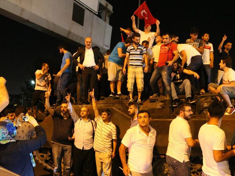 Türken stehen in Istanbul auf einem Panzer.
