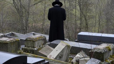 Ein Mann steht im zerstörten jüdischen Friedhof von Sarre-Union in Frankreich.