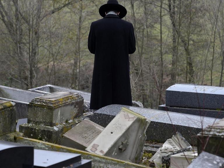 Ein Mann steht im zerstörten jüdischen Friedhof von Sarre-Union in Frankreich.