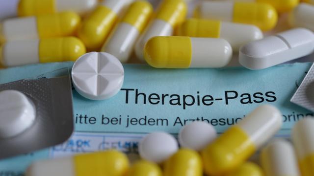 Tabletten und ein Therapie-pass liegen auf einem Tisch, Symbolfoto zum Krankheitsthema Krebs