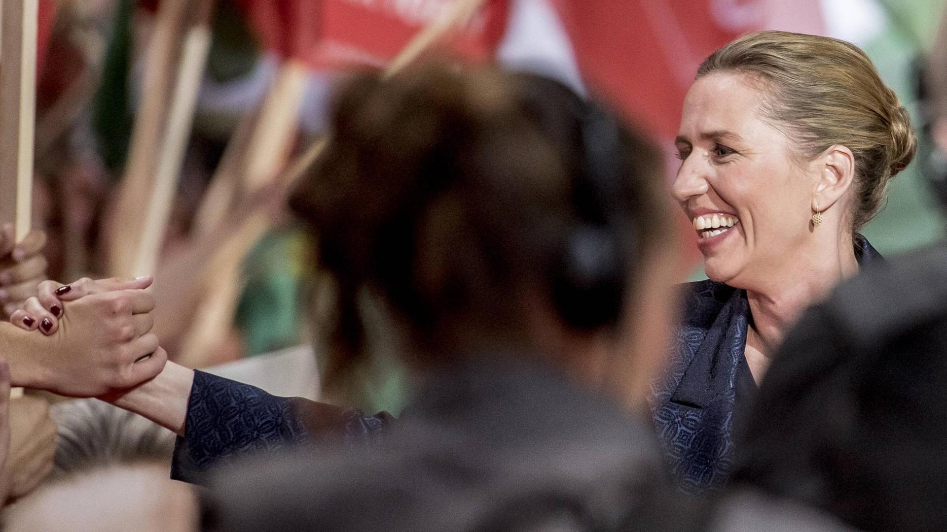 Mette Frederiksen, dänische Sozialdemokratin, schüttelt Unterstützern die Hand. Im Hintergrund sind rote Fahnen zu sehen. Mette Frederiksen, dänische Sozialdemokratin, schüttelt Unterstützern die Hand. Im Hintergrund sind rote Fahnen zu sehen.