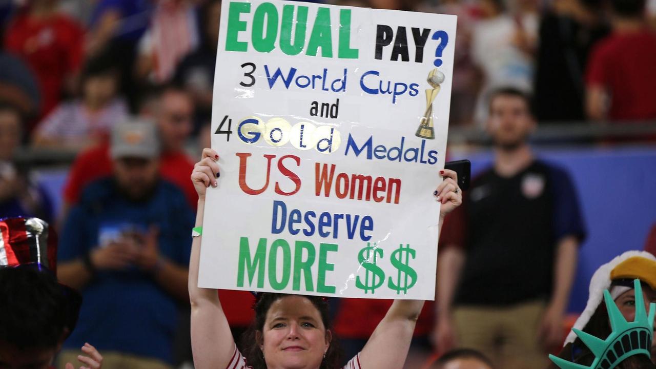 Eine Frau hält am 2. Juli im Stade de Lyon zum WM-Halbfinale ein Plakat hoch mit der Forderung für gleiche Bezahlung im US-amerikanischen Fußball. Eine Frau hält am 2. Juli im Stade de Lyon zum WM-Halbfinale ein Plakat hoch mit der Forderung für gleiche Bezahlung im US-amerikanischen Fußball.