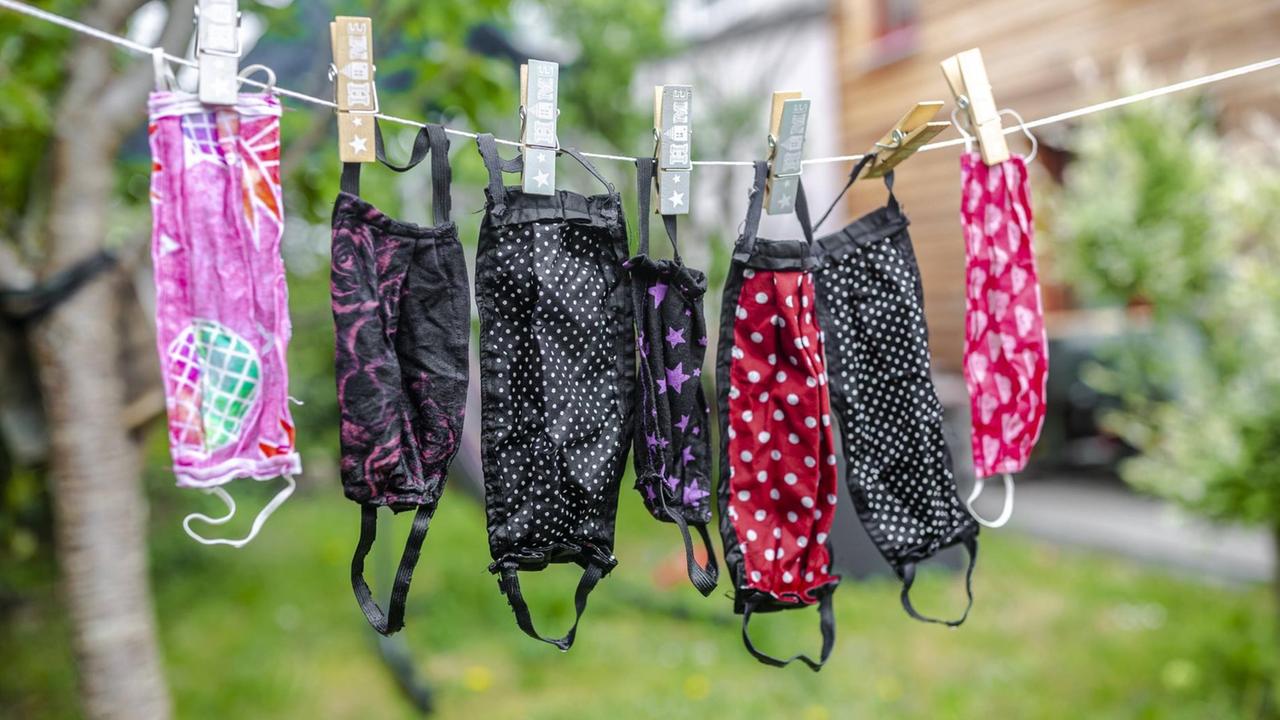 Bunte Stoffmasken hängen an einer Leine Bunte Stoffmasken hängen an einer Leine