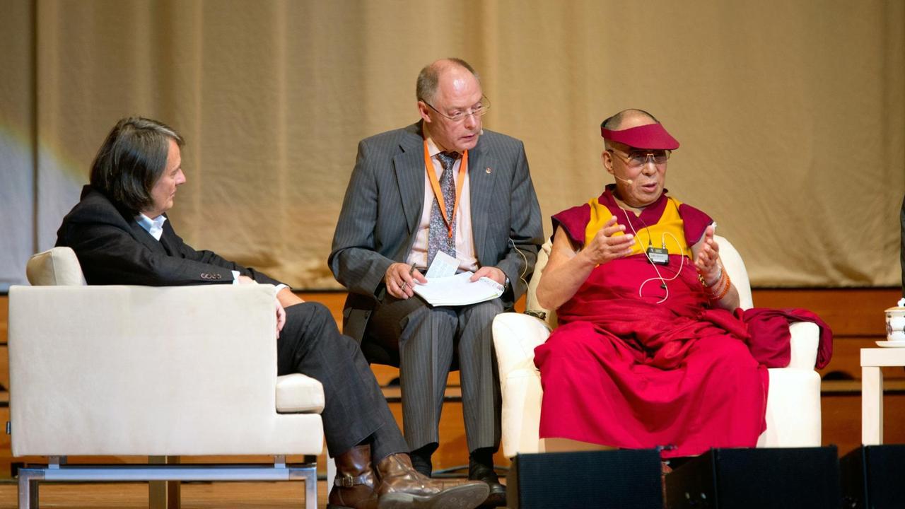 Der Dalai Lama mit seinem Übersetzer Christof Spitz (M) und dem Journalisten Gert Scobel (l) auf einer Diskussionsrunde 2014 in Hamburg.
