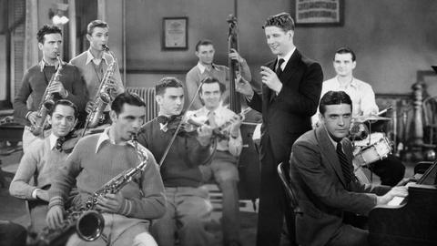 Eine junge Band von jungen Männern spielen Saxophone, Geige und Schlagwerk auf einem Foto in shhwarz-weiß.