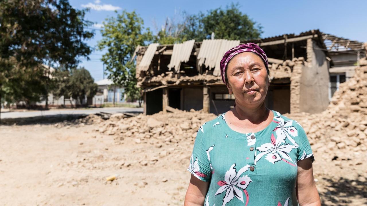 Ruine, davor steht eine Frau mit Kopftuch, halbnah. Ruine, davor steht eine Frau mit Kopftuch, halbnah.