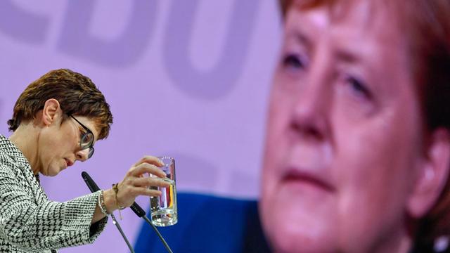 Annegret Kramp-Karrenbauer spricht beim Bundesparteitag der CDU im Dezember 2018 in Hamburg, im Hintergrund ist auf einer Leinwand groß das Gesicht von Angela Merkel zu sehen