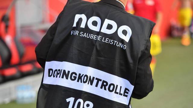 Ein Dopingkontrolleur der NADA (Nationale Anti Doping Agentur) bestellt einen Spieler zur Dopingprobe.