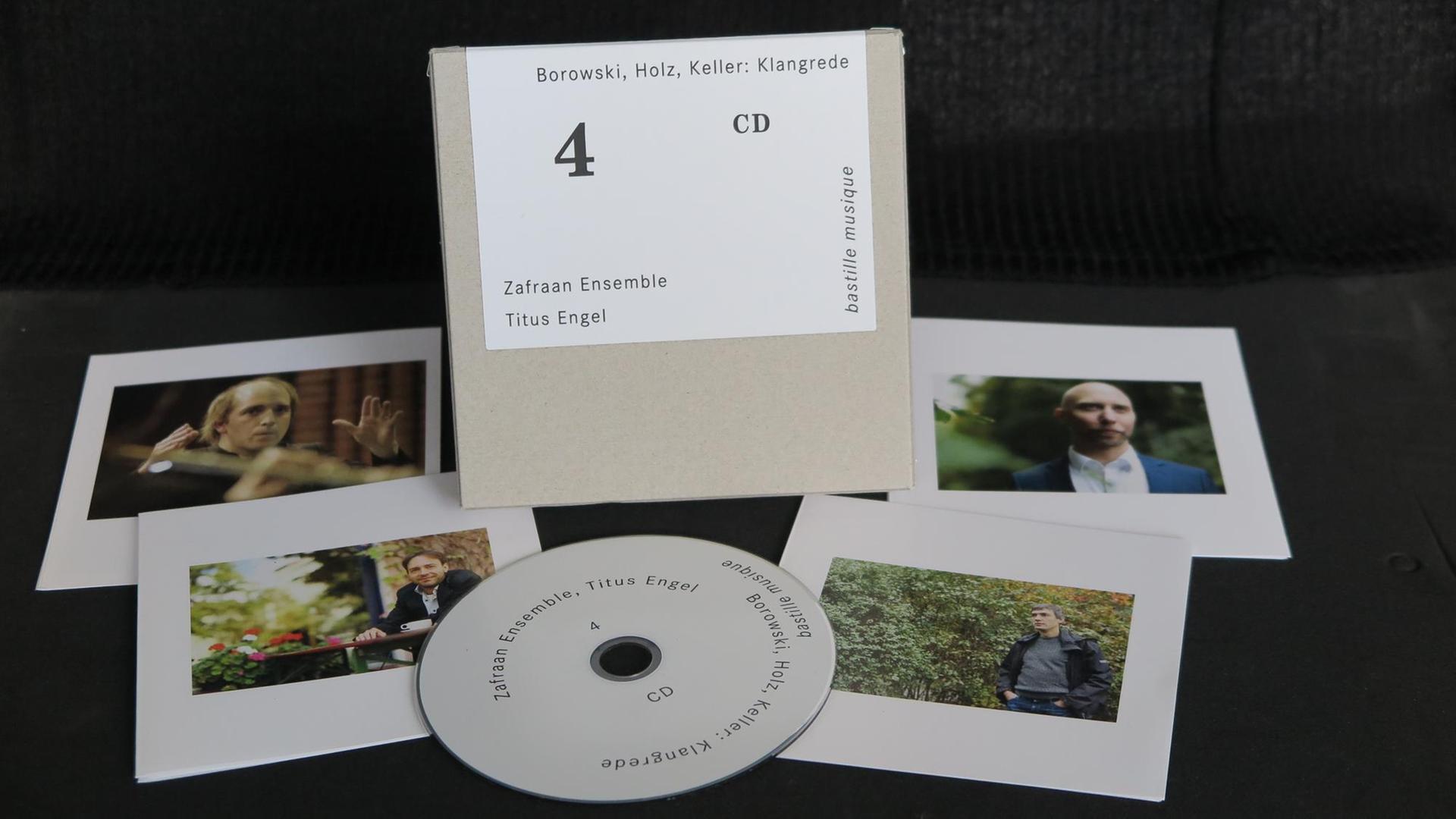 Eine CD liegt ausgepackt mit Cover und Booklets auf schwarzem Hintergrund